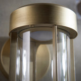 Close-up of Lighting No.1 Yeldmoor die-cast LED outdoor wall light showing brushed gold cylindrical top and clear glass cylinder shade.