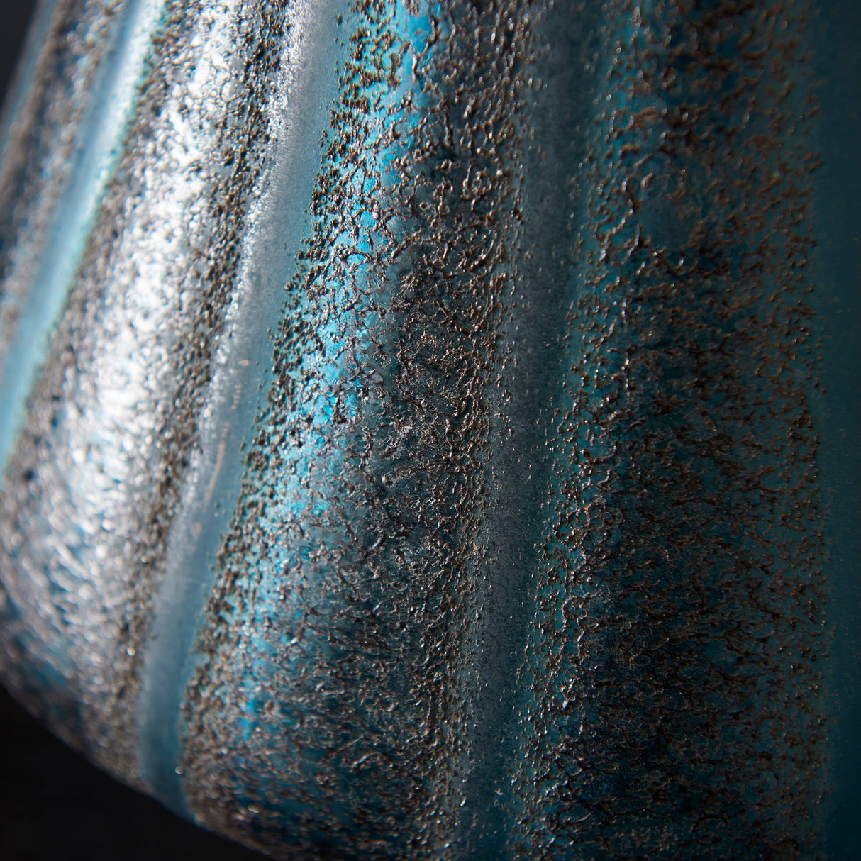 Close-up of the Foxleigh table lamp's textured turquoise glass body, showing ribbed contours and a mottled gold-flecked surface.