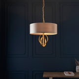Sparrowmere 3 light pendant by Lighting No.1 with mink fabric drum shade and gold leaf double hoops, hung from a chain against a dark blue panelled wall.