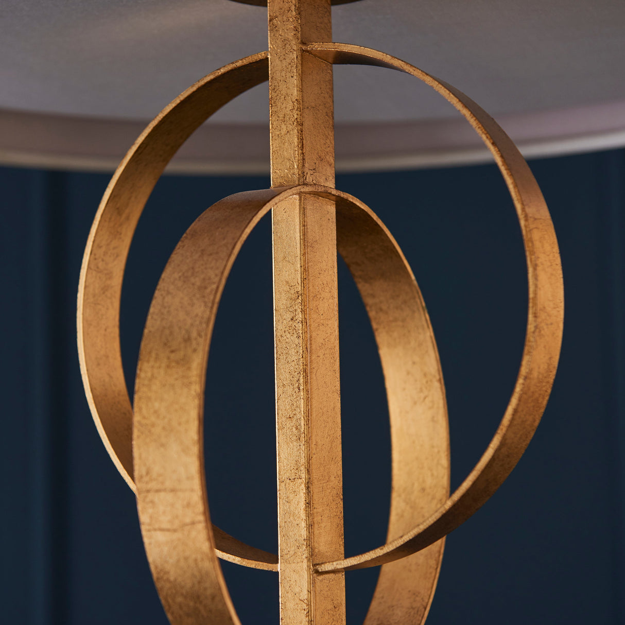 Close-up of the Lighting No.1 Sparrowmere pendant showing two interlocking gold leaf hoops around the central stem beneath a mink fabric shade.