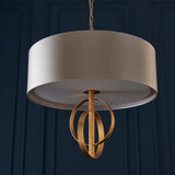 Sparrowmere Double Hoop 3 light pendant from Lighting No.1, mink fabric drum shade with gold leaf metal hoops, shown against a dark blue panelled wall.