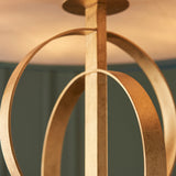 Close-up of the Sparrowmere Double Hoop XL pendant by Lighting No.1, showing two gold leaf metal hoops and ceiling plate against a teal wall.
