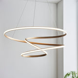 Lighting No.1 Tolmere Spiral Large Pendant in natural metal finish, coiled ribbon form hanging from thin cables in a bright neutral interior.