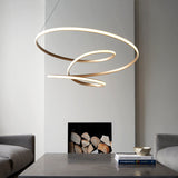 Tolmere Spiral Large Pendant in natural metal finish, coiled into an illuminated spiral above a console table by a fireplace in a living room.