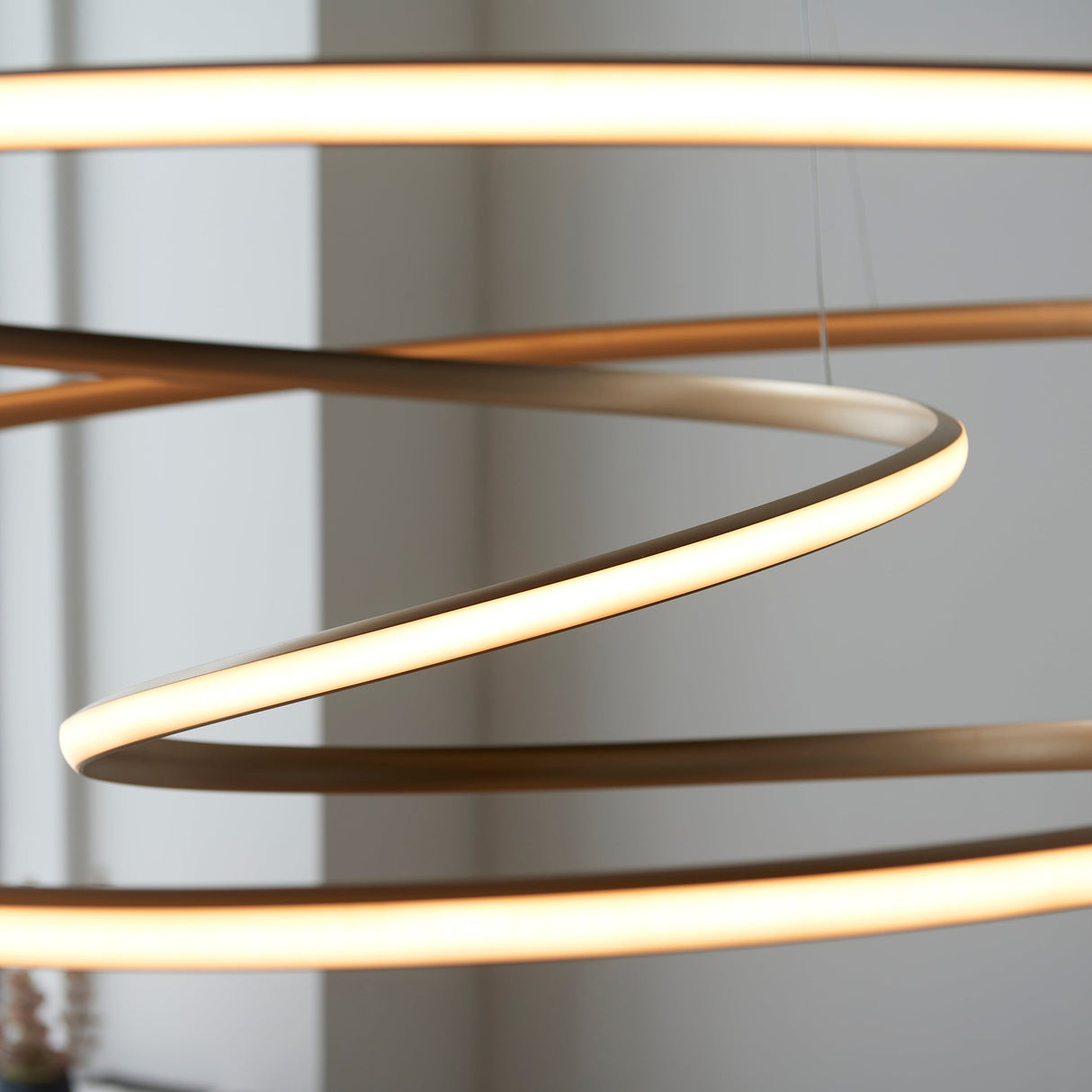Close-up of the Tolmere Spiral Grand Pendant in natural finish by Lighting No.1, showing the coiled metal ribbon with warm integrated LED glow.