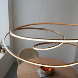 Tolmere Spiral Grand Pendant in natural metal finish with integrated warm LED, suspended above a round wooden dining table with fruit bowl.