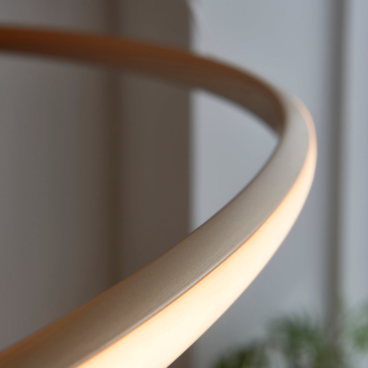 Close-up of the Lighting No.1 Tolmere Spiral Grand Pendant in natural finish, showing the curved metal ribbon with integrated warm LED glow along its underside.