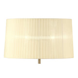 The Loewe 3 Light Floor Lamp features a brass stand and a cylindrical cream shade with subtle vertical stripes, shown against a white background. The thin brass stand is minimally visible beneath the elegant lampshade.