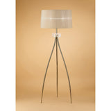 The Loewe 3 Light Floor Lamp features a soft bronze pleated shade atop three slender brass legs with a central glass accent, offering elegant, dimmable lighting that stands out beautifully against a warm beige background.