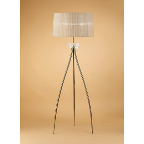 The Loewe 3 Light Floor Lamp features a soft bronze pleated shade atop three slender brass legs with a central glass accent, offering elegant, dimmable lighting that stands out beautifully against a warm beige background.