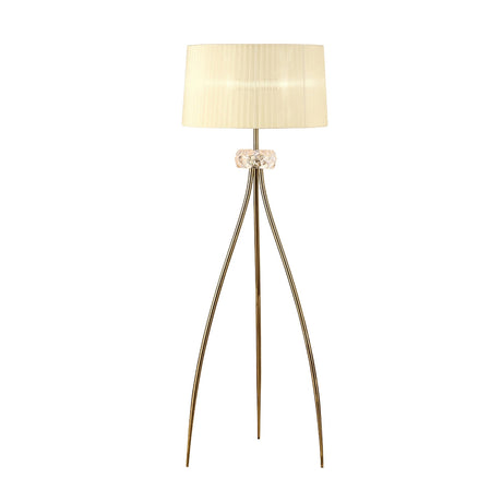 The Loewe 3 Light Floor Lamp features a brass finish with three slender gold legs, a decorative glass accent near the top, and a wide cream fabric shade.