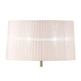 A close-up of the Loewe 3 Light Floor Lamp, featuring a slim brass base and a cylindrical white pleated shade, against a plain white background.