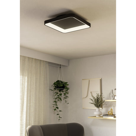 Loretello LED Flush Ceiling Light, 35 x 35cm square fixture in black with rounded corners and a white diffuser ring, shown mounted on a living room ceiling above a seating area.