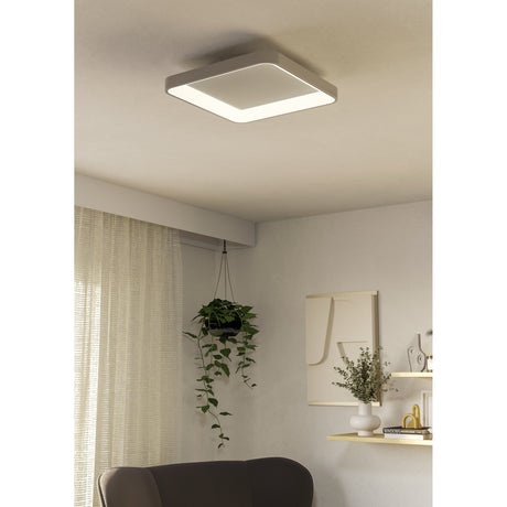 Loretello LED flush ceiling light in white, square 35 x 35cm design with recessed diffuser, shown illuminated on a living room ceiling above a seating area.