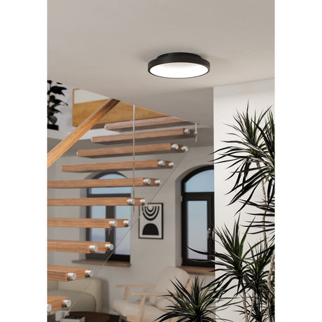 Loretello Smart LED Flush Ceiling Light 35cm in black, round fixture with white diffuser mounted on a hallway ceiling above a wooden staircase.