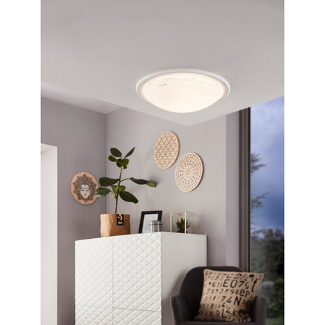 Lornette flush ceiling light in white, round glass shade with clear outer band, fitted in a hallway corner above a white cabinet.