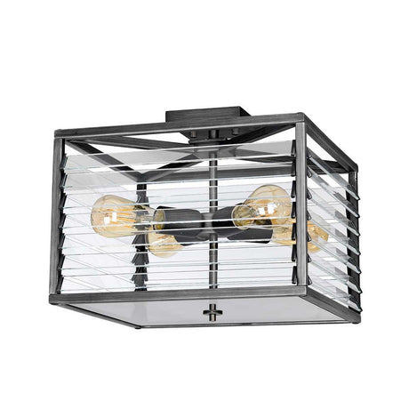 The Louvre 4 Light Flush in a sleek graphite finish features a square, modern design with clear glass panels and four exposed bulbs that emit a warm glow. This fixture strikes the perfect balance between industrial and minimalist styles, making it an ideal choice for those seeking industrial lighting with a stylish edge.