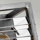 Close-up of a contemporary, geometric metal structure featuring parallel horizontal bars and a transparent component, reminiscent of the Louvre 2 Light Wall Light in Graphite, set against a light gray background. The design embodies an industrial and minimalist style, making it ideal for filament-style bulbs in industrial-themed interiors.