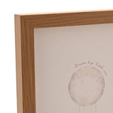 Close-up of the natural wood frame corner on the Dream Big Moon Balloon wall art, showing the woodgrain finish and a watercolour-style moon print with "Dream big little one" text.