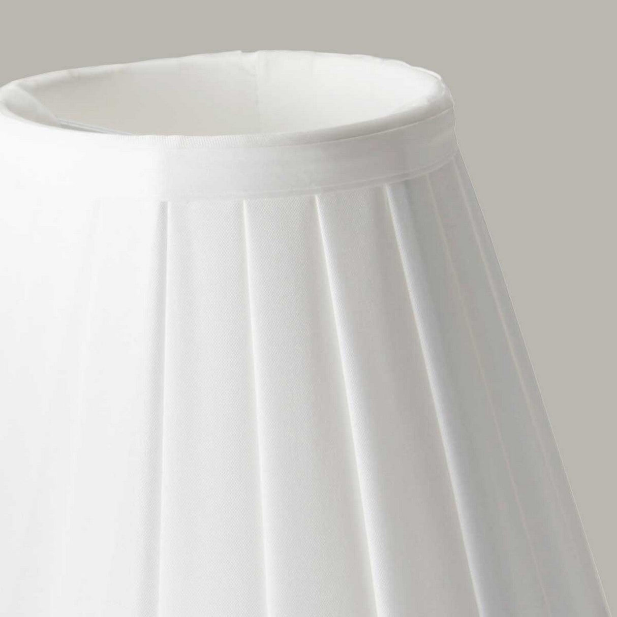 Close-up of the Clip Shades Pleated White Candle Shade, featuring a classic tapered design and crafted from pleated polycotton fabric, set against a plain gray background. A perfect addition to your lighting fixtures collection.