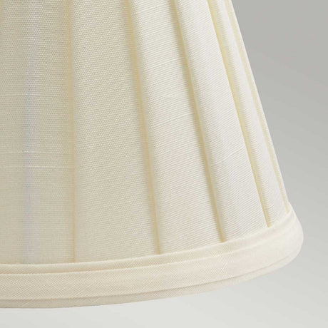 A detailed view of the Clip Shades Pleated Ivory Candle Shade reveals vertical pleats, with the polycotton fabric texture softly illuminated against a neutral backdrop.