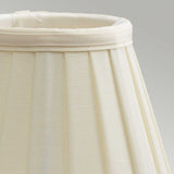 A close-up of the Clip Shades Pleated Ivory Candle Shade, featuring vertical pleats made from polycotton fabric, set against a neutral background. The fabric's texture is subtly visible, casting gentle shadows along the pleats.