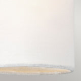 Close-up of a Clip Shades - Ivory Linen cylindrical lampshade against a neutral background. The woven fabric, featuring its subtle grid pattern, is enhanced by ambient lighting, beautifully highlighting the material's texture.