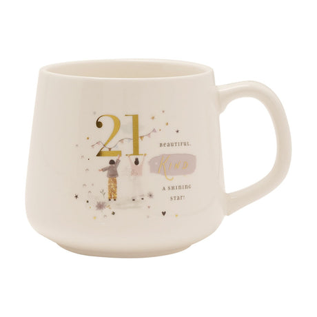 Cream stoneware mug with a gold "21" and illustrated figures hanging bunting, plus "Beautiful, kind, a shining star" text, shown on a plain white background.