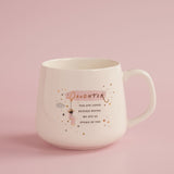 White stoneware mug with pink background, featuring "Daughter" in gold script, a loving message, a figure on a swing, cloud, and scattered gold and pink stars.