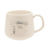 Cream stoneware mug with C-handle featuring "Daddy you are my hero" in gold script, a dad and child with balloon illustration, and gold hearts and stars, on a plain white background.