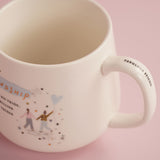 White stoneware mug with Fabulous Friend printed inside the handle, a partial friendship quote, and illustrated figures with a heart balloon, on a pink background.