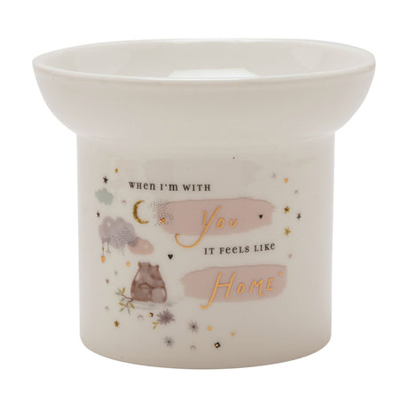 White ceramic wax melt burner with round body and wide dish top, featuring two bears, a gold moon, clouds and "You" and "Home" in gold script on pink accents.