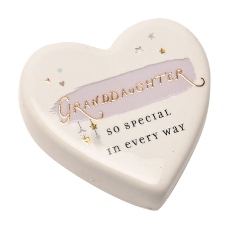 White ceramic heart keepsake token with "Granddaughter, so special in every way" in gold and dark lettering, lilac brush stroke, and star and heart accents, on a white background.