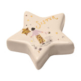 White ceramic star-shaped keepsake token with glossy finish, featuring "Sister" in gold script above an illustrated girl in a lilac top holding a star balloon, surrounded by small hearts and flowers.
