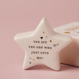 White ceramic star keepsake token with glossy finish, printed "You are the one who just gets me!" with small heart, star and flower accents, set against a pink background.