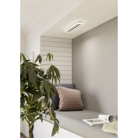 Macchioni LED Panel Light, an elongated oval white ceiling fixture 55 x 12cm, shown recessed into a grey alcove above a cushioned seating nook.