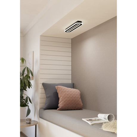 Macchioni LED Panel Light in black and white, an oval ceiling fixture with a black ring and white diffuser, fitted into a recessed nook above a cushioned window seat.