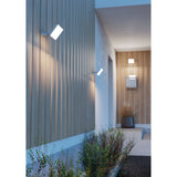 Machio LED Flood Light 30W in white, shown mounted on a slatted wall by a front entrance, with a rectangular aluminium body on an adjustable wall bracket casting warm downward light.