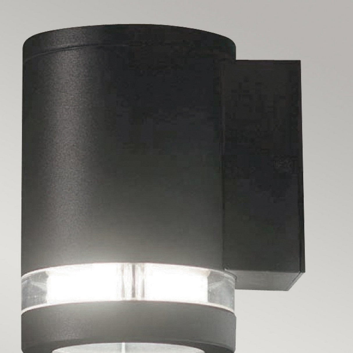 The Magnus 1 Light Outdoor Wall Light in graphite boasts a modern, sleek cylindrical design, complete with a frosted glass section that emits soft white light. Rated IP44, it is an ideal fixture for enhancing your exterior space.