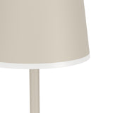Close-up of the Mannera-L LED floor lamp in sand, showing the bell-shaped plastic shade with white trim edge atop a slim aluminium stem, on a plain white background.