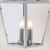 A close-up of the Mansion 3 Light Outdoor Chain Pendant in polished nickel, featuring a lantern-style design with three exposed, glowing bulbs. This fixture showcases a sleek, modern aesthetic with a harmonious blend of glass and polished nickel finishes.