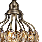 Close-up of the Marisa 1 Light Crystal Table Lamp in antique brass, featuring curved metal arms and amber teardrop-shaped crystals that reflect warm light—a modern take on the classic crystal table lamp.