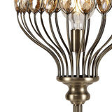 Close-up of the Marisa 1 Light Crystal Floor Lamp in antique brass, featuring a metallic base and multiple curved arms with teardrop-shaped faceted crystal accents around an exposed bulb.