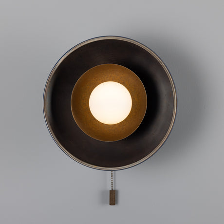 Marrakesh Brass Pull Chain Wall Light with a round dark outer shade, inner brass cup, and central glass globe, shown front-on with pull chain on a light grey background.