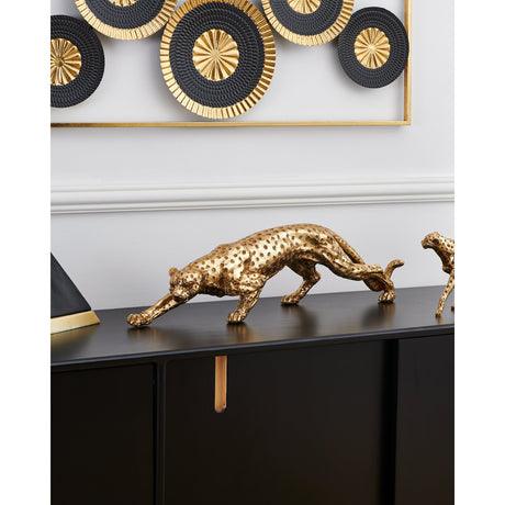 Gold resin leopard figurine, Menjangau Leopard Ornament 17.5cm, shown mid-stalk with textured spotted finish on a black sideboard beneath wall art.