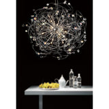 Diyas Messe 24 light crystal semi-flush ceiling light in polished chrome, with looping wires and faceted crystal spheres, shown above a white table.