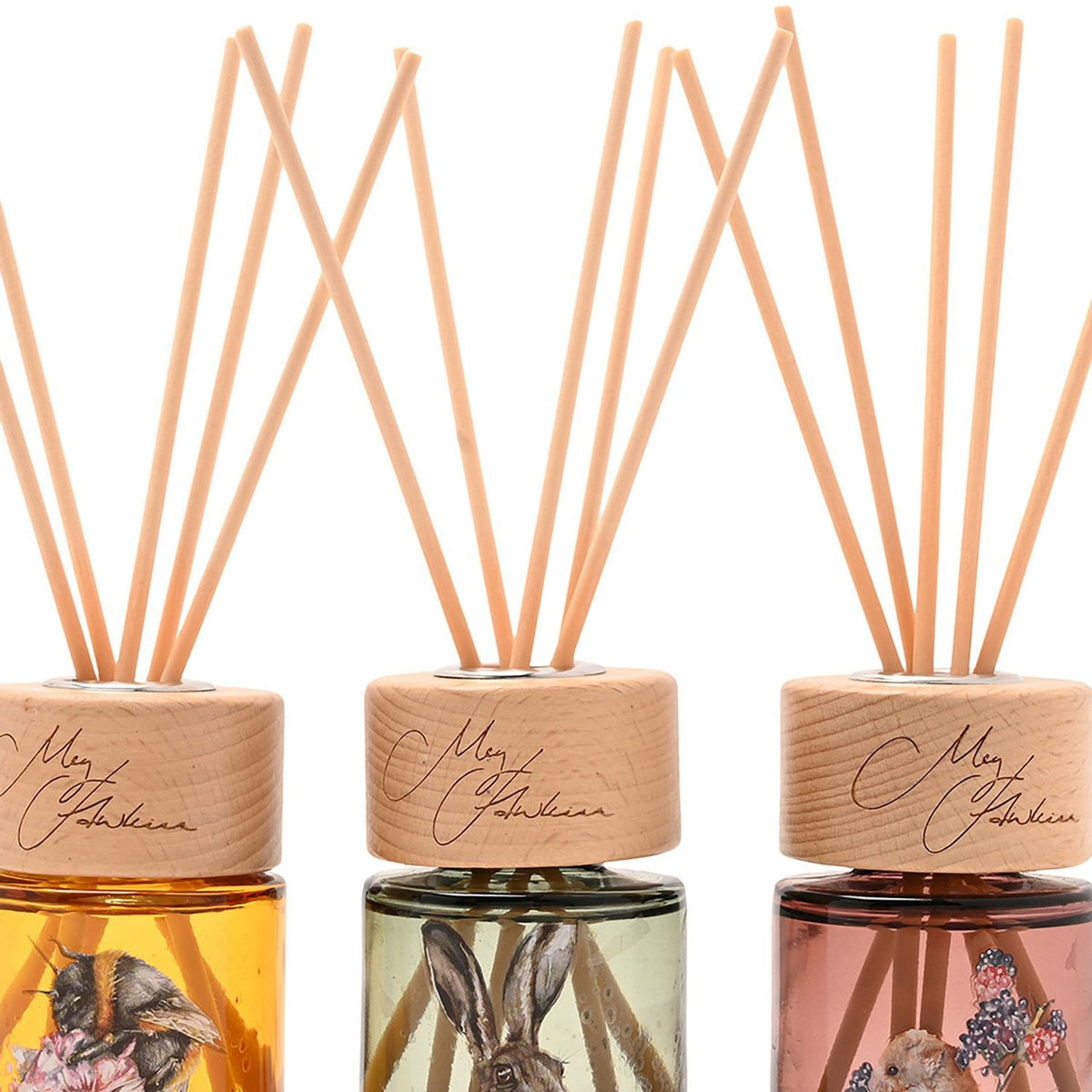 Set of three mini reed diffusers with wooden caps and reeds, featuring amber, sage green, and dusty pink glass bottles illustrated with a bee, hare, and mouse.