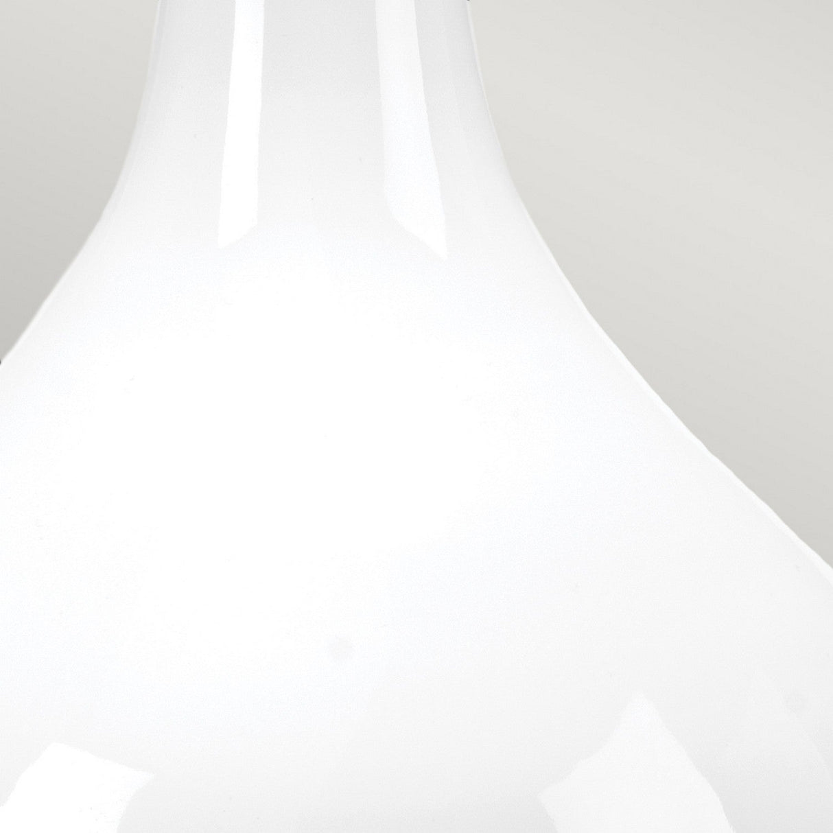 A close-up of the Milo 1 Light Table Lamp reveals its smooth, glossy white surface and elegantly curved form, reminiscent of a minimalist ceramic or glass structure. It stands against a light grey background with understated touches of polished nickel and subtle orange accents.