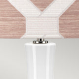 Close-up of a contemporary table lamp featuring a polished nickel base with a pastel pink ceramic touch, complemented by a beige and white geometric patterned fabric shade, set against a light grey background. This minimalist yet sophisticated design echoes the refined elegance found in the Milo 1 Light Table Lamp - Polished Nickel/Pink.