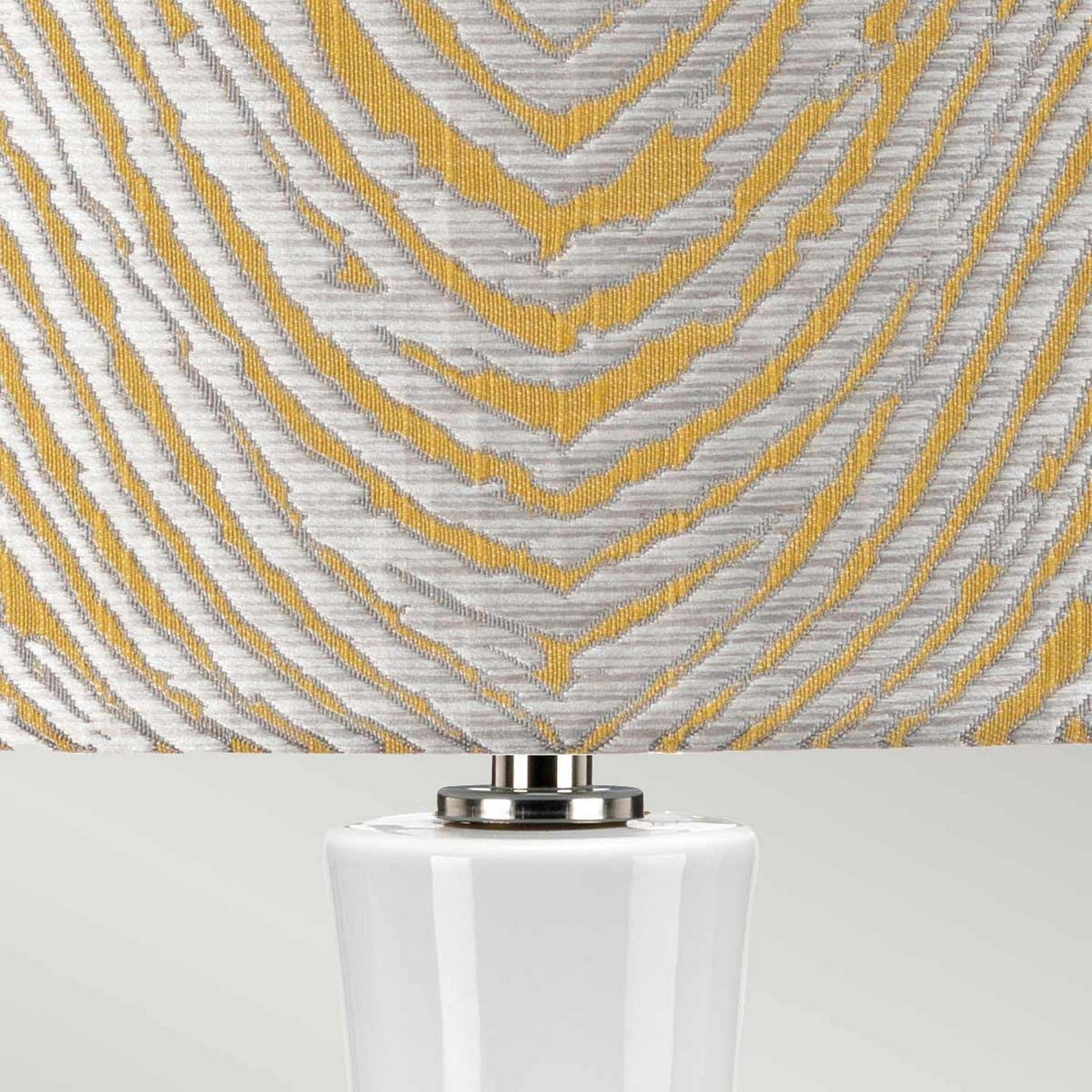 Close-up of this decorative Milo 1 Light Table Lamp - Polished Nickel/Yellow features a textured yellow drum shade adorned with a silver and gold geometric pattern. Its white base is accented with polished nickel, offering an elegant touch to any room.